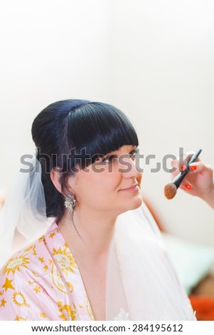 Makeup bride brunette in a dressing gown sits