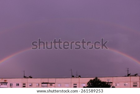 Rainbow over house. Weather in city.Cloudy sky with rainbow. City landscape with rainbow and clouds.