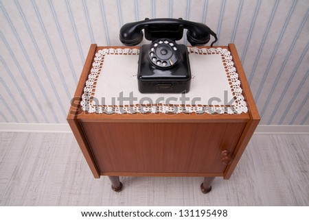 old fashioned piece of furniture with an old-style black telephone on it