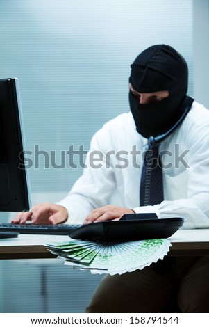 A desk clerk wearing a balaclava while doing some swindle about money (focus on the money)