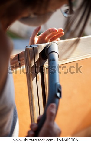 Do it yourself scene about a woman removing sawdust from her polished window under the sun