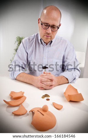 an office worker observes sadly that there are no more money left even after breaking the piggy bank.