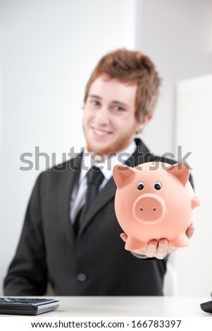 Self confident Young redheaded businessman passing you a piggy bank
