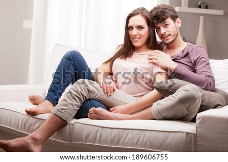 couple of lovers in relax glaze on a sofa in a well lit living room