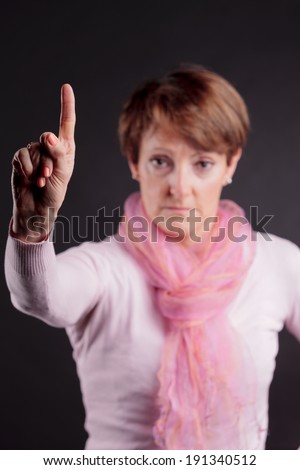 mature woman with a raised hand with index up denying or imposing