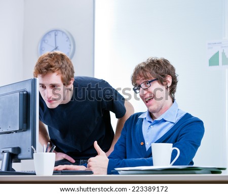 a couple of young employees in an office working together to achieve common goals
