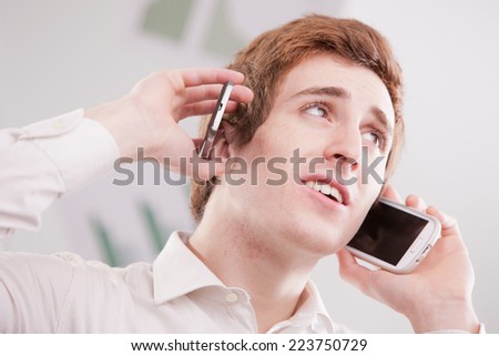a happy geek fan of mobile phones calling with two cellular phones