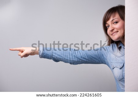 girl pointing out with her entire arm behind the wall