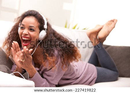 african american woman singing on a sofa wearing white headphones