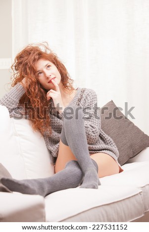 Red Headed very cute girl thinking about the future on her sofa in her living room