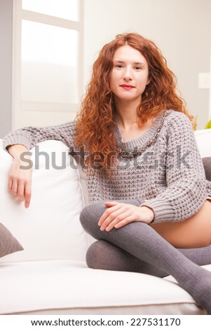 Red Headed very cute girl self-confident on her sofa in her living room