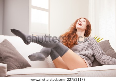 Red Headed very cute girl smiling on her sofa in her living room