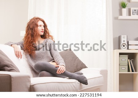 Red Headed very cute girl self-confident on her sofa in her living room