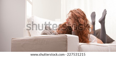 Red Headed very cute girl thinking seriously on her sofa in her living room