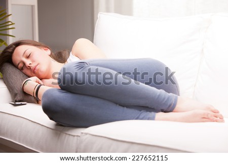 brown haired girl sleeping on her couch in a white living room