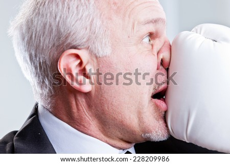 business man receiving a punch in the face with a white boxing glove