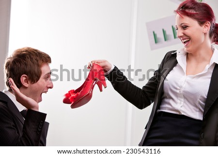 humorous scene of a woman giving a red pair of high heels red shoes to a business man