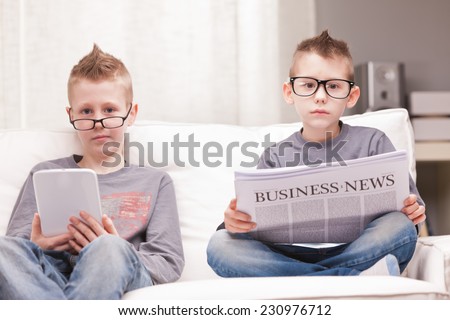 two little boys reading on newspapers or digital devices