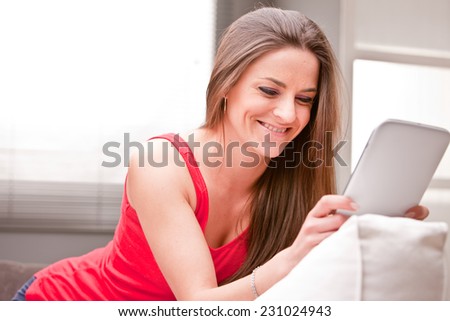 beautiful woman lying on a couch enjoying content on a tablet