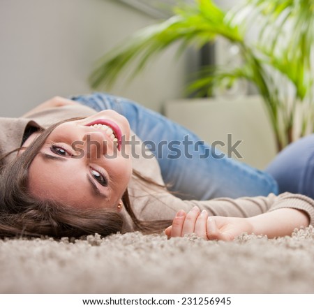 young beautiful woman laughing upside-down on the floor of her living room