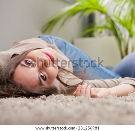 young beautiful woman smiling upside-down on the floor of her living room