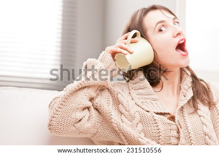 girl listening to a mug making funny faces pretending to hear something amazing
