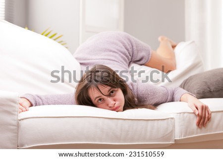 funny girl showing fatigue throwing herself on the sofa in her living room after a long day at work