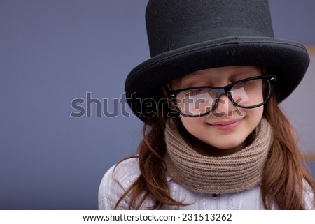 funny little girl smiling satisfied with big glasses and a big top-hat