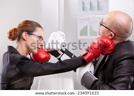 business woman hitting a business man in a box match with a right jab