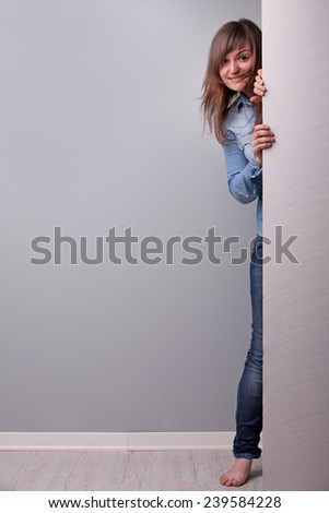 standing barefoot woman showing up behind the wall