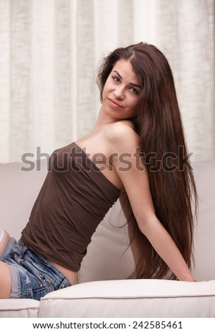 long hair young girl posing on a sofa in her full youth and health