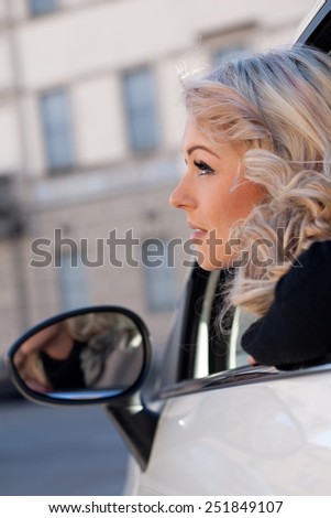 blonde tourist watches something from her car, she\'s blonde and beautiful and she may have spotted something amazing