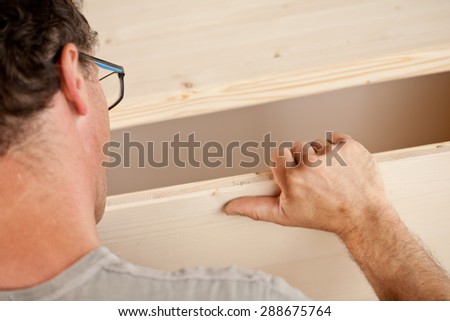 powerful arm and hand of a carpenter placing a component in a piece of handcrafted piece of furniture