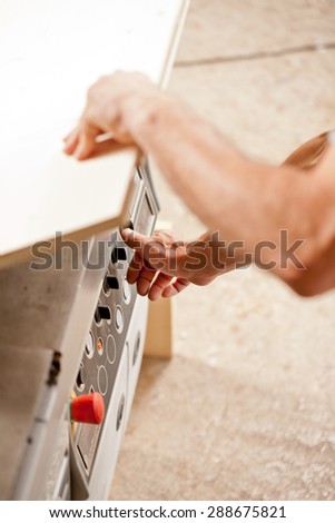 one arm out of focus with a board and all the focus on the hand setting up the control knobs on a carpenter\'s machine in a joiner\'s workshop