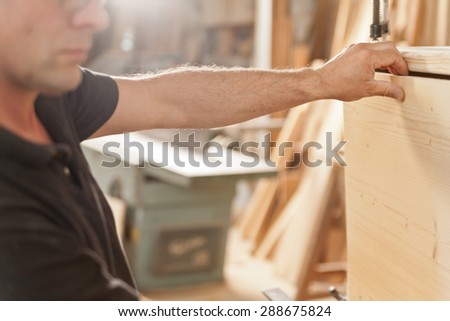 arm and hand of a carpenter carefully placing a component in a piece of handcrafted piece of furniture
