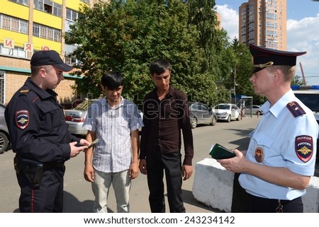 KHIMKI, RUSSIA - AUGUST 9, 2013: Police officers inspect the documents on the streets in the suburban town of Khimki. Patrol and inspection service of the police provides public safety in the city.