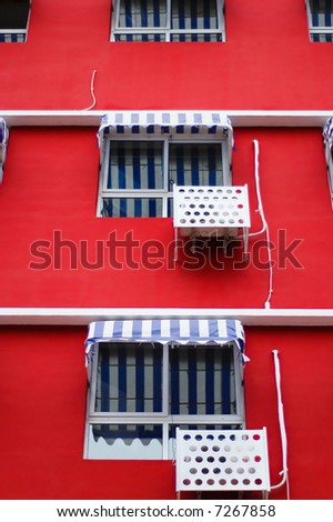 Front facade of a bright red building featuring striped window awnings.