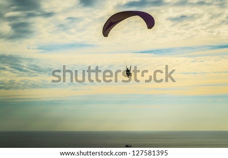 Para glider is flying above the sea in the evening