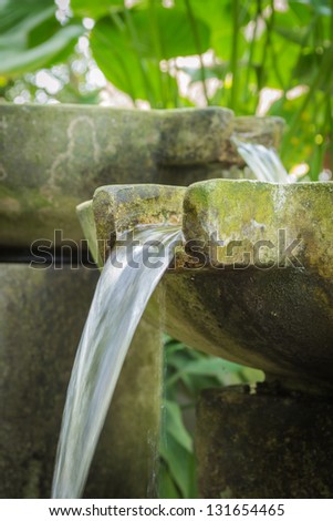 Flowing water from stone basin in the garden