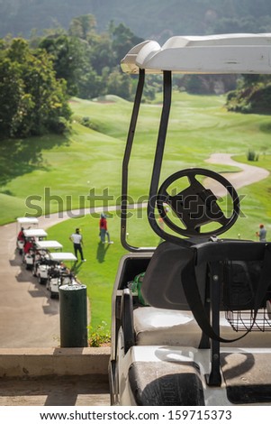 Golf club cars at golf field with golfers are on started point