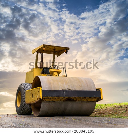Road roller at road construction site with cloudy blue sky during sunset