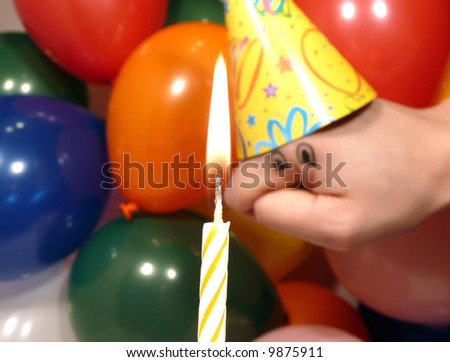 Silly hand puppet dressed up for a birthday party looking at a lit candle