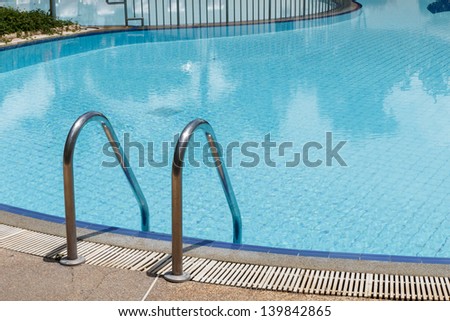 A view of alight clear blue swimming pool with steel ladder