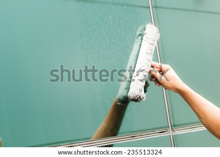 Hand of worker cleaning windows in building-1