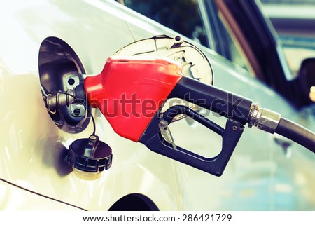 Red pumping fuel oil in car at gas station, retro