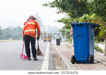 Blue  trash bin with  worker cleaning the road background