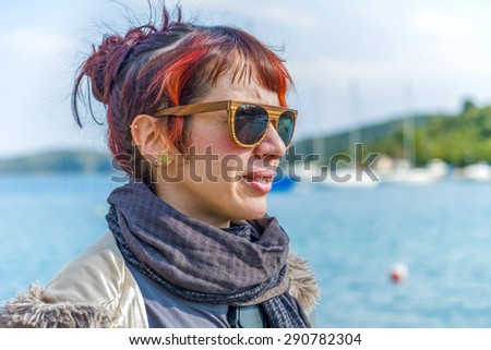 Woman on the beach, next tot fishing boats on a sunny day in Greece.