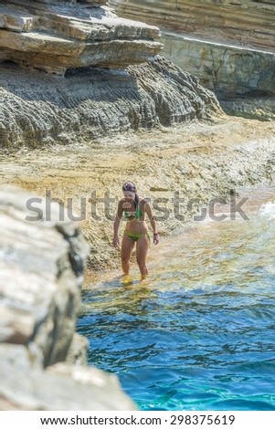 Pretty young woman among the impressive rocks of Preveli beach in Crete, Greece.