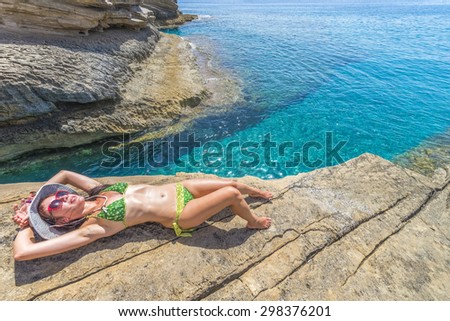 Pretty young woman among the impressive rocks of Preveli beach in Crete, Greece.