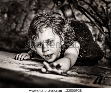 Close up of little girl dramatically reaching up on grubby wall